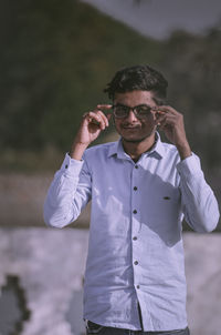 Portrait of young man wearing sunglasses standing outdoors.