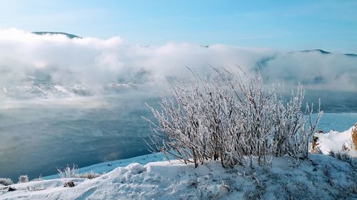 Scenic view of snow covered land against cloudy sky