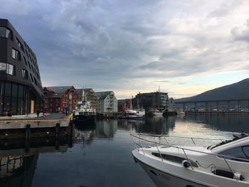 Sailboats moored on canal by buildings in city against sky