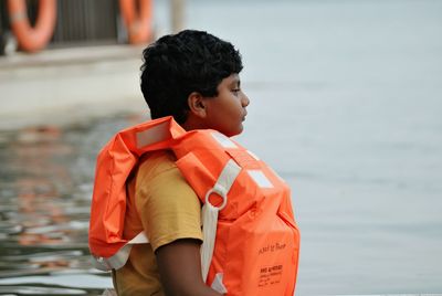 Close-up of boy wearing life jacket in sea