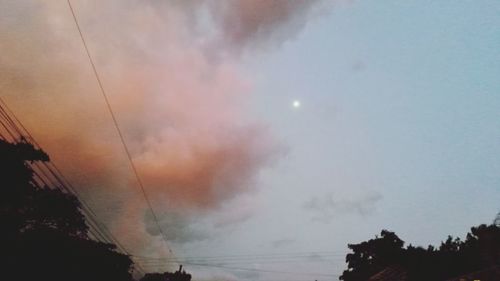 Low angle view of power lines against cloudy sky