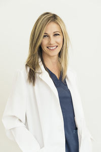 Portrait of female doctor smiling while standing against white background