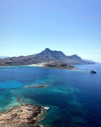 Scenic view of sea and mountains against clear blue sky