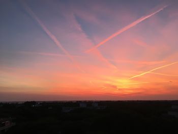 Scenic view of vapor trails in sky during sunset