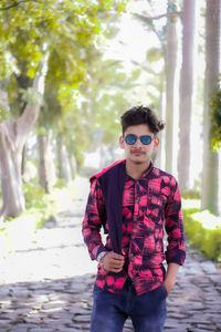 Portrait of teenage boy wearing sunglasses standing in park