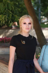 Portrait of beautiful young woman standing at park