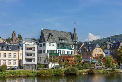 Buildings by river in town against sky