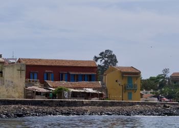 Houses by river and buildings against sky