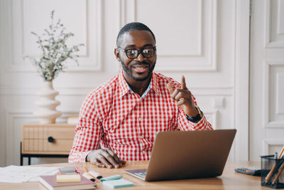 Male friends using laptop at desk in office