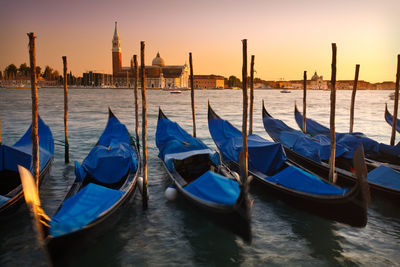 Boats moored in canal at sunset