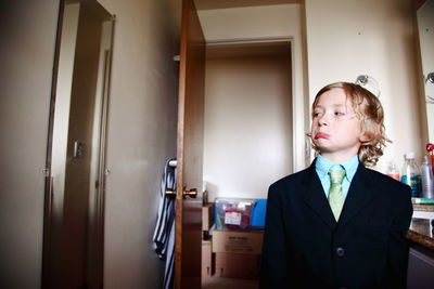 Boy in suit making face while standing in bathroom