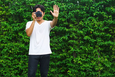 Full length of man photographing against plants