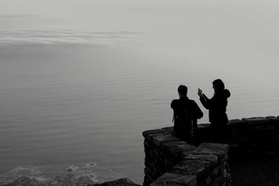 People looking at sea against sky