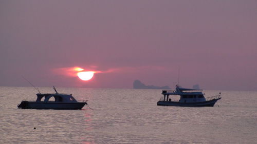 Boat on sea against sky during sunset