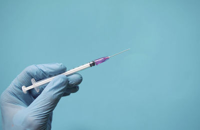 Low angle view of person hand against blue background