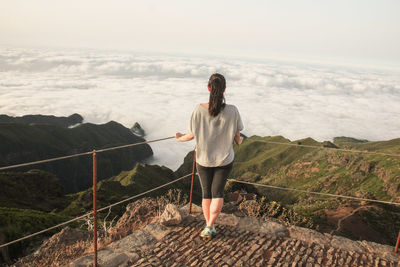 Full length rear view of woman looking at sea by railing