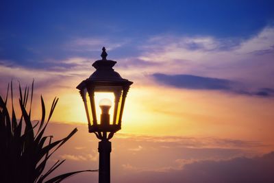 Low angle view of illuminated street light against sky at sunset