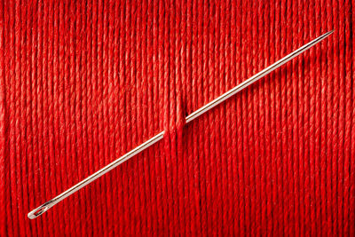 Close-up of sewing needle in red thread