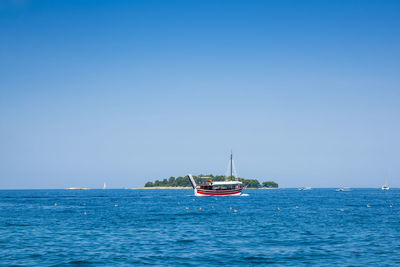 Sailboat on sea against clear blue sky