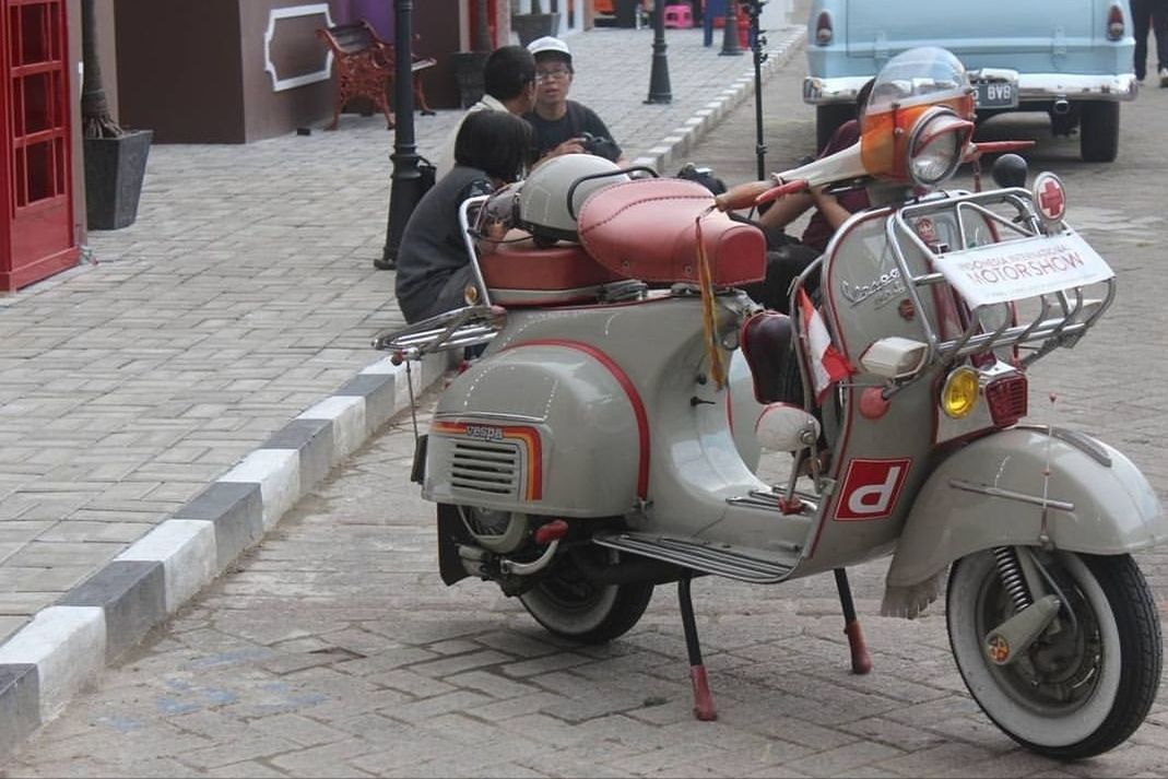 mode of transportation, land vehicle, city, transportation, street, incidental people, architecture, day, real people, building exterior, stationary, scooter, built structure, footpath, motorcycle, car, motor scooter, road, motor vehicle, travel, outdoors, paving stone