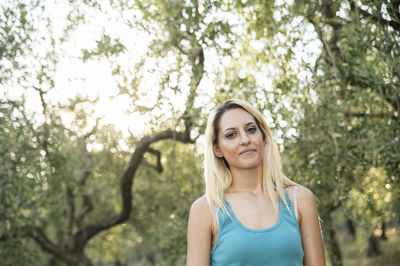 Portrait of young woman standing against trees