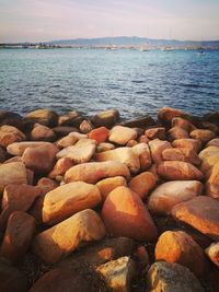 Pebbles on beach against sky during sunset