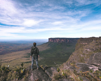 Rear view of man walking on mountain against sky