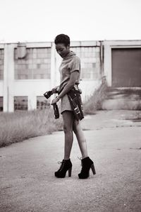 Fashionable woman tying shirt on road