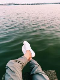 Low section of man sitting by lake