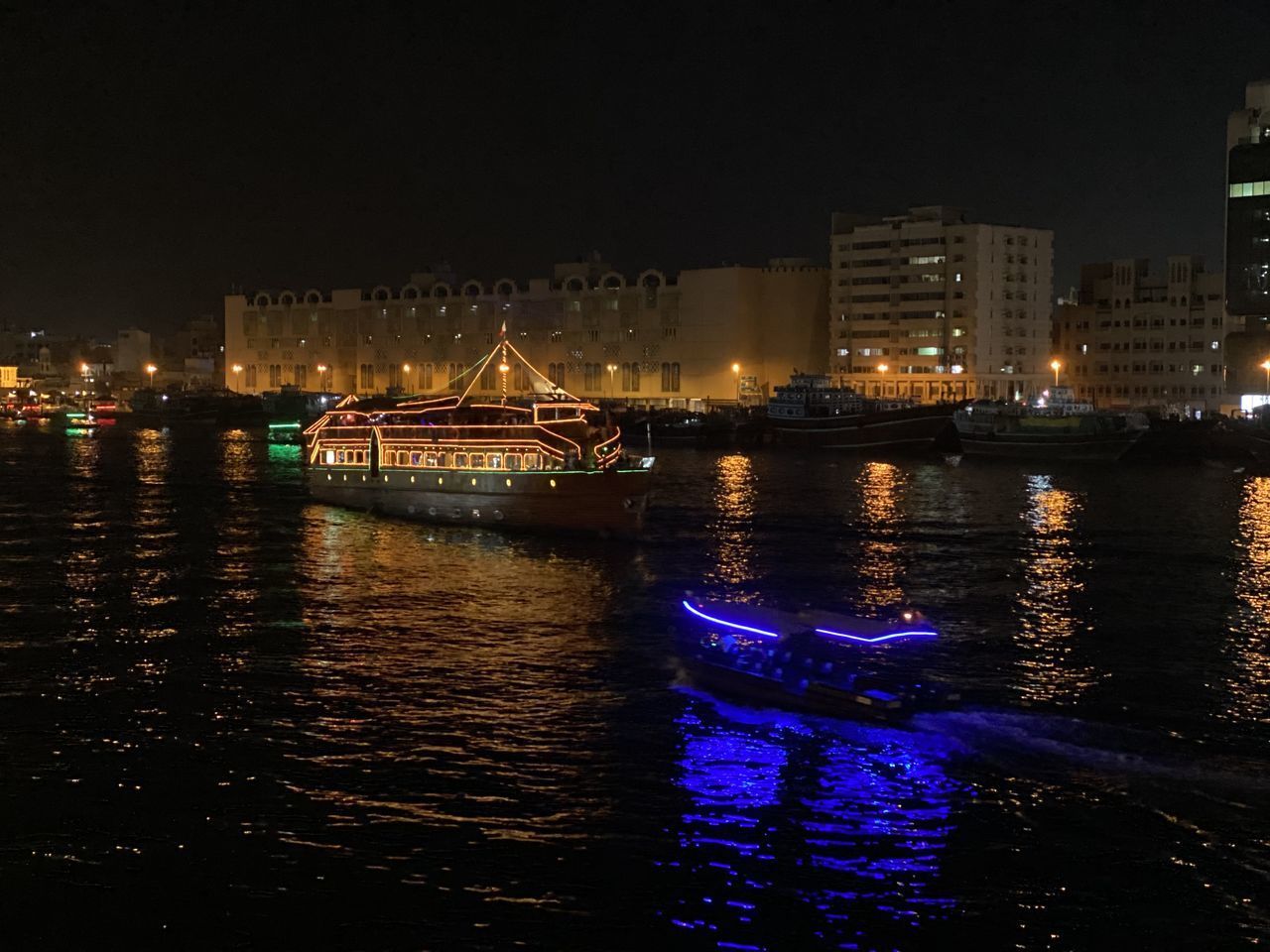 ILLUMINATED BUILDINGS BY RIVER AT NIGHT