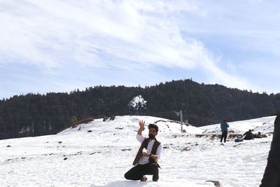People sitting on snowy mountain against sky