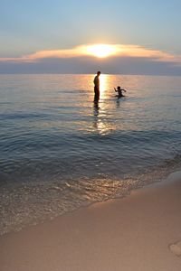 Scenic view of people on beach at sunset