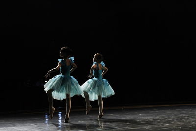 Group of people dancing against black background