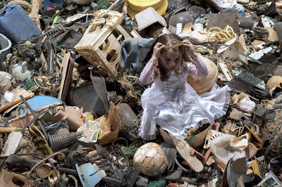 High angle view of girl sitting in garbage
