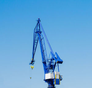 Low angle view of crane against clear blue sky