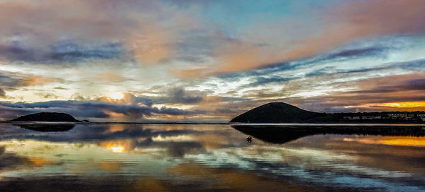 Scenic view of lake against dramatic sky during sunset