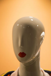 Close-up of female mannequin with red lipstick against colored background