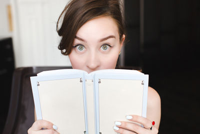 Surprised girl covers her face with a book