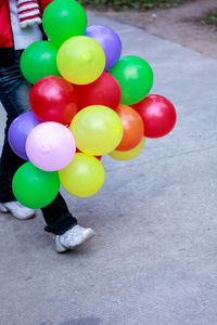 Low section of woman with balloons on street