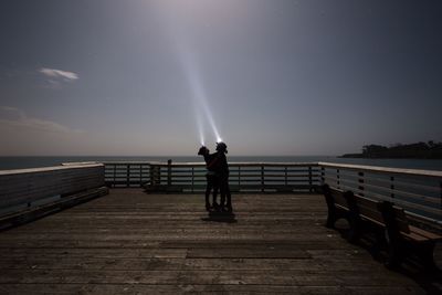 View of couple standing on pier at night