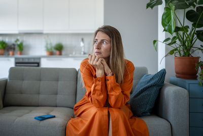 Young woman sitting on sofa at home