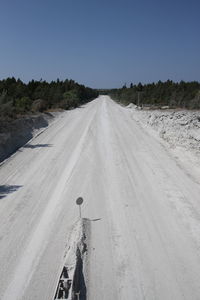 White road passing through landscape against clear sky