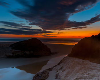 Scenic view of sea against dramatic sky during sunset