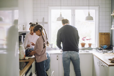 Siblings preparing food with father working in kitchen at home