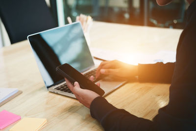 Midsection of person using smart phone on table