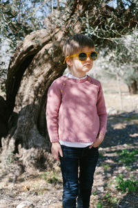 Portrait of boy wearing sunglasses standing against tree