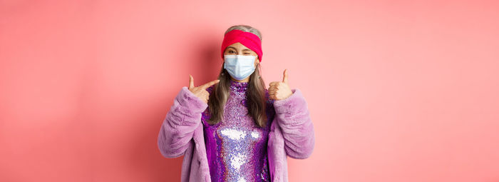 Cropped hand of woman holding paper currency against pink background