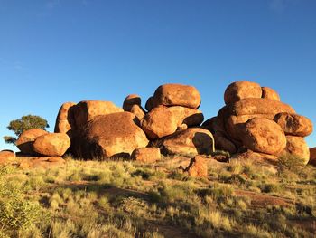 Rocks on field against clear blue sky