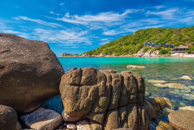 Scenic view of rocks by sea against sky