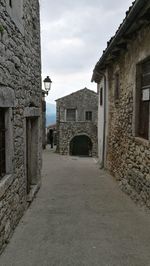 Walkway amidst buildings against sky